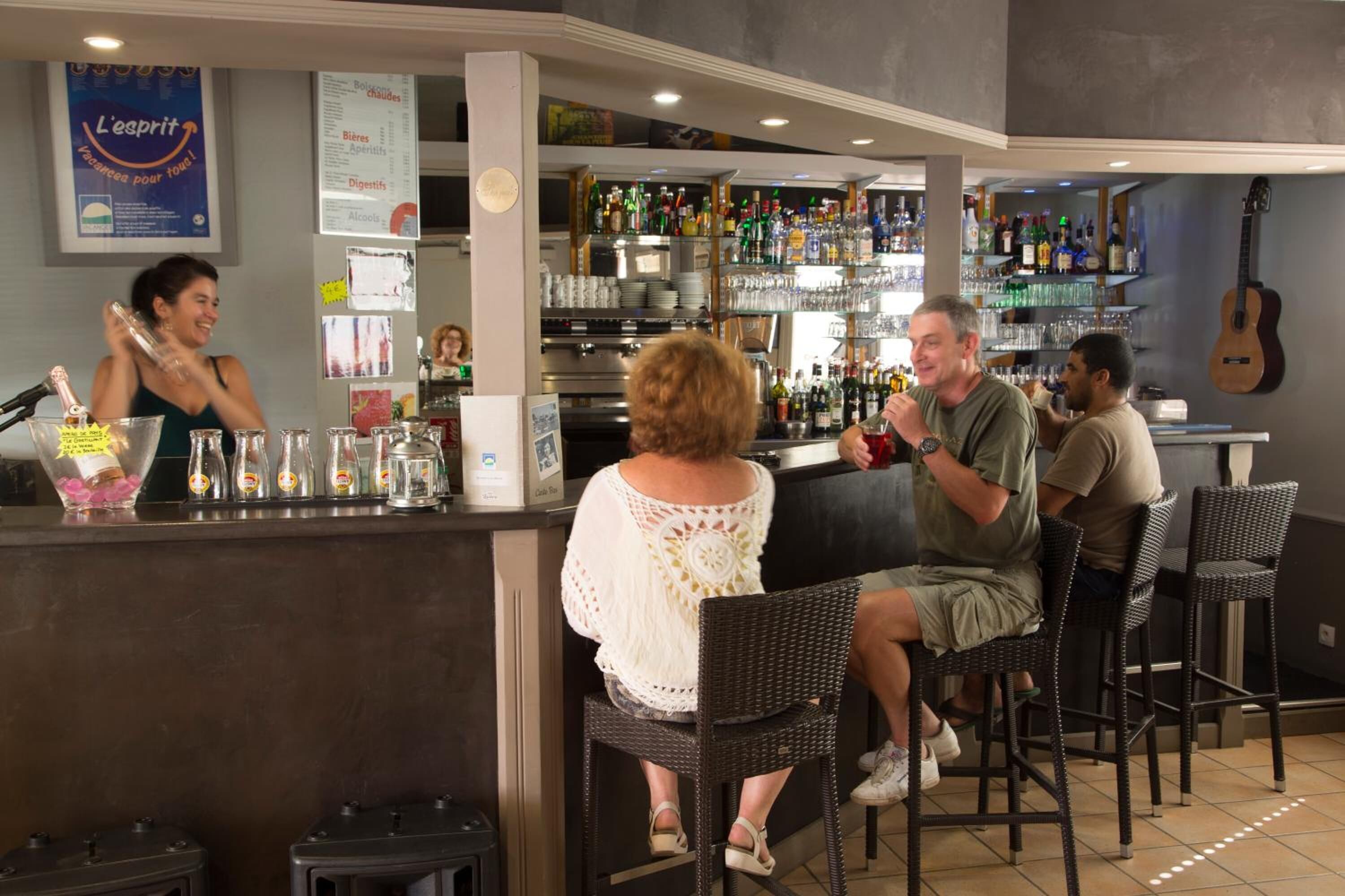 Een bar met een toonbank, barstoelen en diverse flessen en glazen.