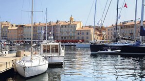 A marina with boats docked, buildings in the background, and a clear sky. - Vacances Passion La Grande Bastide (Le Lavandou)