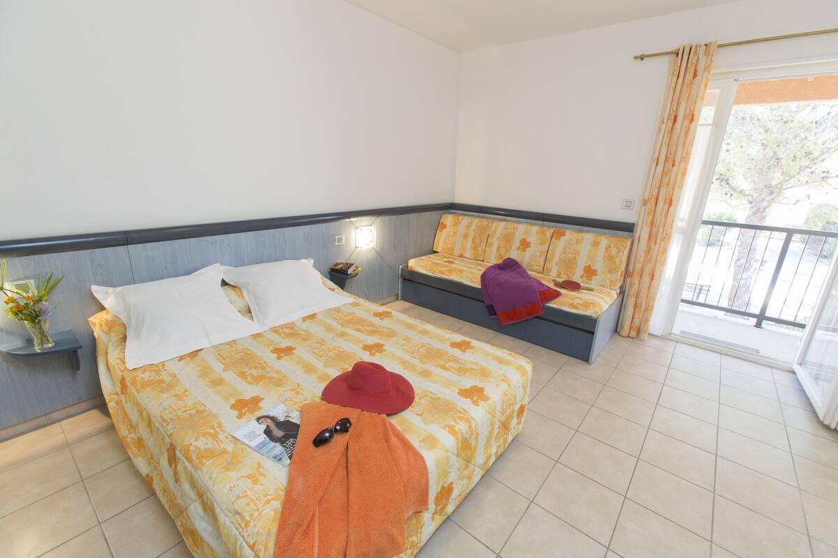 Une chambre d’hôtel avec un lit, un canapé, une table de chevet et une fenêtre avec des rideaux.