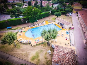 Vue aérienne d’un quartier résidentiel avec une piscine entourée de chaises longues et d’une petite table.