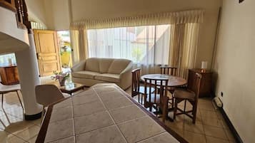 A hotel room with a dining table, a sofa, and a chair.