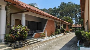 A covered outdoor area with steps leading to a seating area, surrounded by plants and a paved walkway. - Hotel Resort Obelisco (La Asunción)
