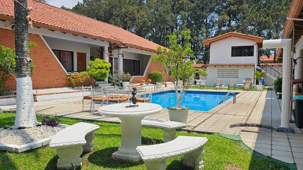 A pool area with a tiled deck, outdoor seating, and a small fountain. - Hotel Resort Obelisco (La Asunción)