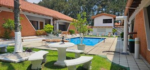 A pool area with a tiled deck, outdoor seating, and a small fountain. - Hotel Resort Obelisco (La Asunción)