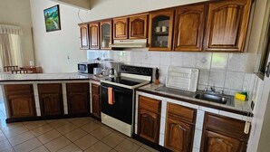 A kitchen with wooden cabinets, a microwave, an oven, and a sink. - Hotel Resort Obelisco (La Asunción)