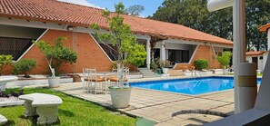 A residential property with a swimming pool, outdoor seating, and a well-maintained garden. - Hotel Resort Obelisco (La Asunción)