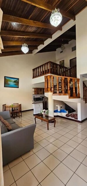 Un vaste espace de vie doté d’un haut plafond, d’un escalier et d’un coin repas.