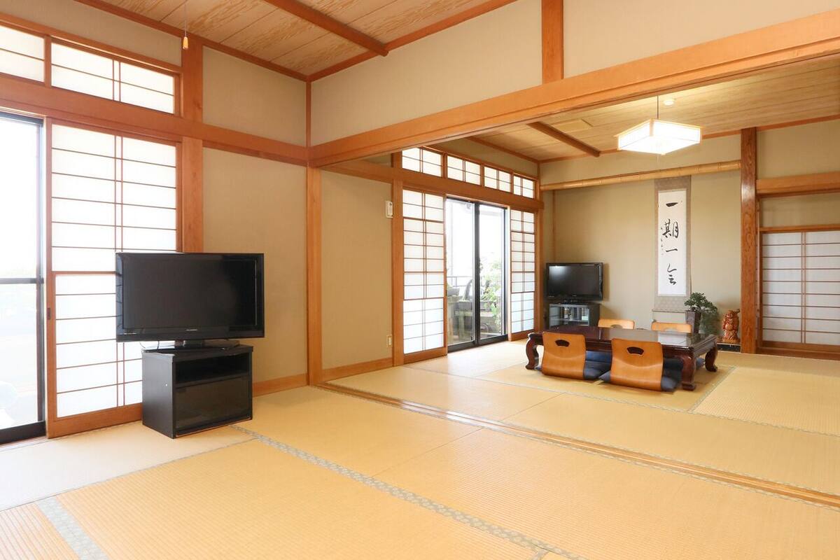 A traditional Japanese room with tatami flooring, a television, and a sliding door.