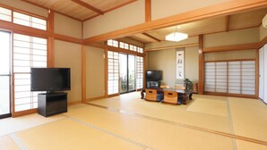 Ein traditioneller japanischer Raum mit Tatami-Bodenbelag, einem Fernseher, einer Schiebetür und einem Tisch aus Tatami-Matten.
