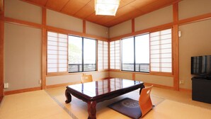 Ein traditioneller japanischer Raum mit Tatami-Boden, einem niedrigen Tisch, gleitenden Shoji-Türen und einem Fernseher.