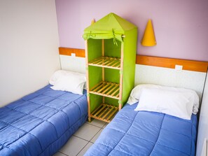 A room with two single beds, each with blue bedding and white pillows. A green, house-shaped bunk bed is positioned between the beds. - Vacances Passion - Leon Les Genets (Léon)