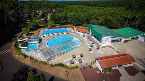 Un complejo turístico con múltiples piscinas, tumbonas y una zona cubierta.