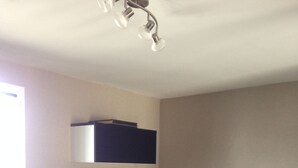 Una cocina moderna con encimera de madera, armarios negros, estufa a gas, una planta en maceta y una ventana con persianas.