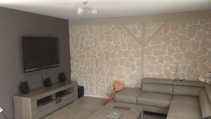 Una sala de estar con pared de diseño de piedra, un televisor de pantalla plana, un sofá y una mesa de centro.