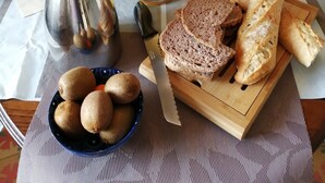 A breakfast table set with croissants, bread, a coffee pot, a glass of orange juice, and a bowl of kiwis. - Maison du Canal (Villeneuve-les-Beziers)