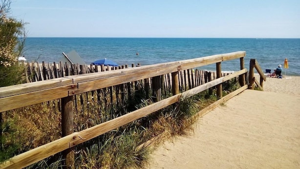 A wooden boardwalk leading to a sandy beach with a clear view of the ocean. - Maison du Canal (Villeneuve-les-Beziers)