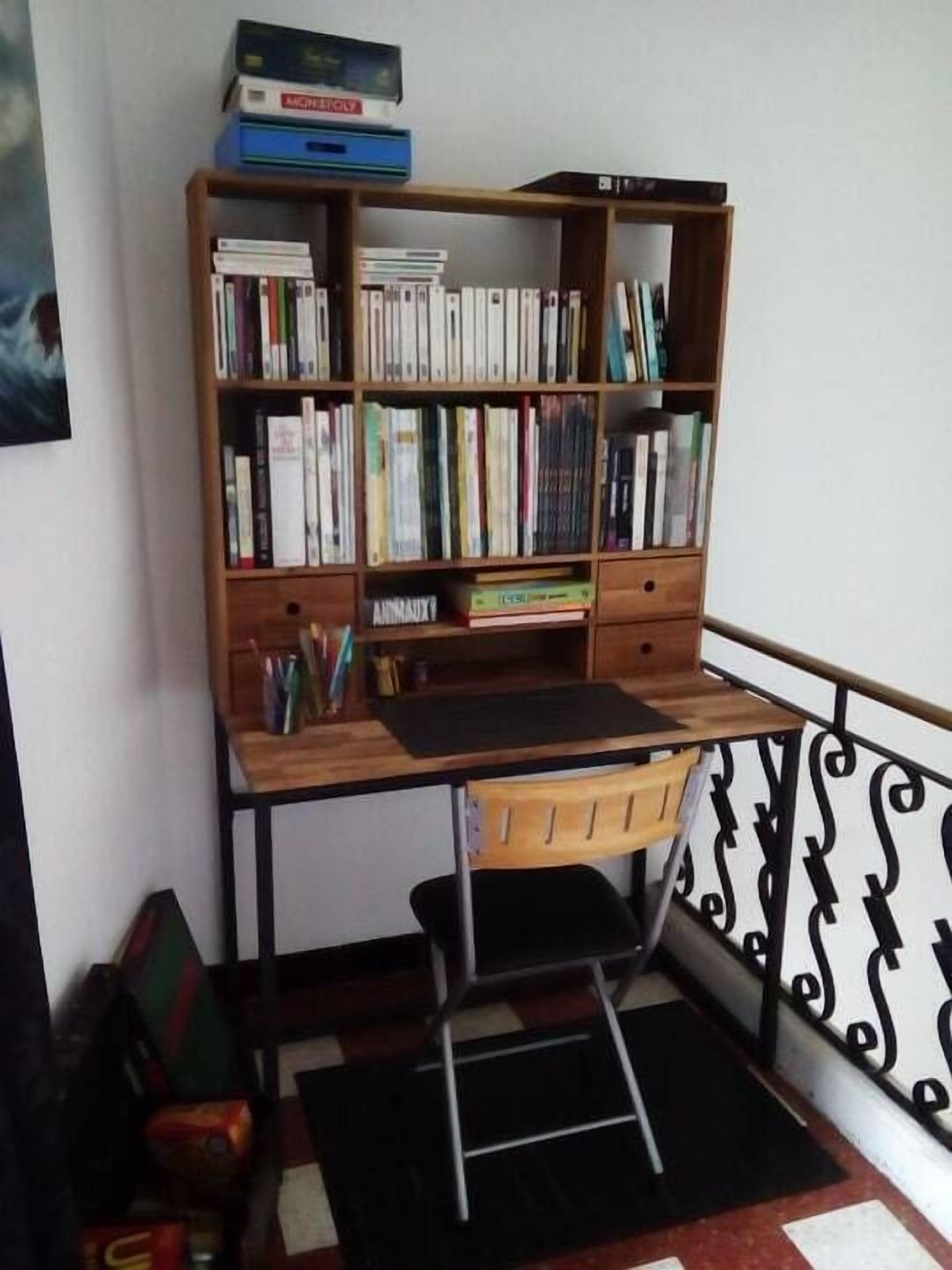 A study area with a wooden desk, bookshelves, and a ladder.