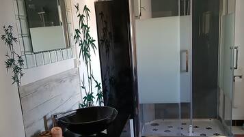 Ein Badezimmer mit einem schwarzen Waschbecken, einem Spiegel, einer Toilette und einer Duschkabine.
