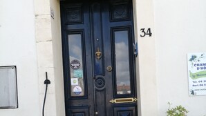 A black door with the number 34, a small mailbox, and two potted plants on the steps. - Maison du Canal (Villeneuve-les-Beziers)