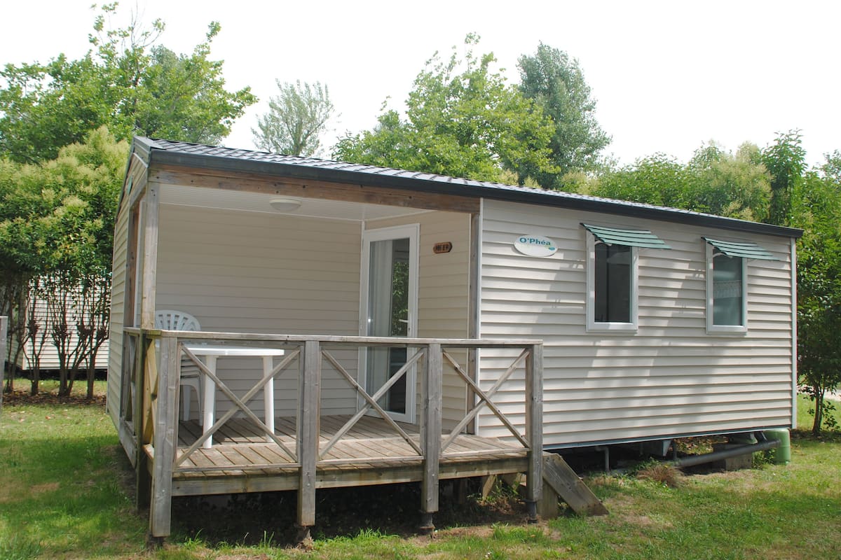 Une petite maison mobile d’un seul étage, dotée d’une terrasse en bois et d’un porche couvert.