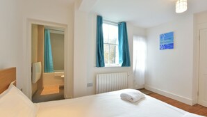 Ein Hotelzimmer mit Bett, einem Fenster mit Vorhängen, einem Heizkörper und einem Bild an der Wand.