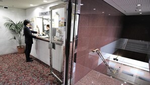 A reception area with a 'FRONT' sign, a reception desk, a potted plant, and a glass elevator shaft. - Royal Hotel Shinokubo (Tokyo)