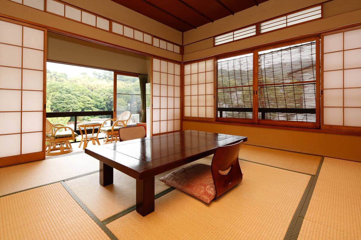 Ein traditioneller japanischer Raum mit Tatami-Boden, einem niedrigen Tisch und verschiebbaren Türen.