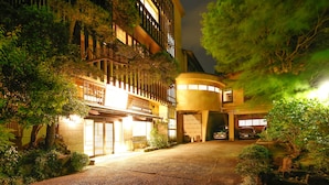 A building with a curved facade, a gated entrance, and a parking area. - Albergo Yuraku (Yugawara)