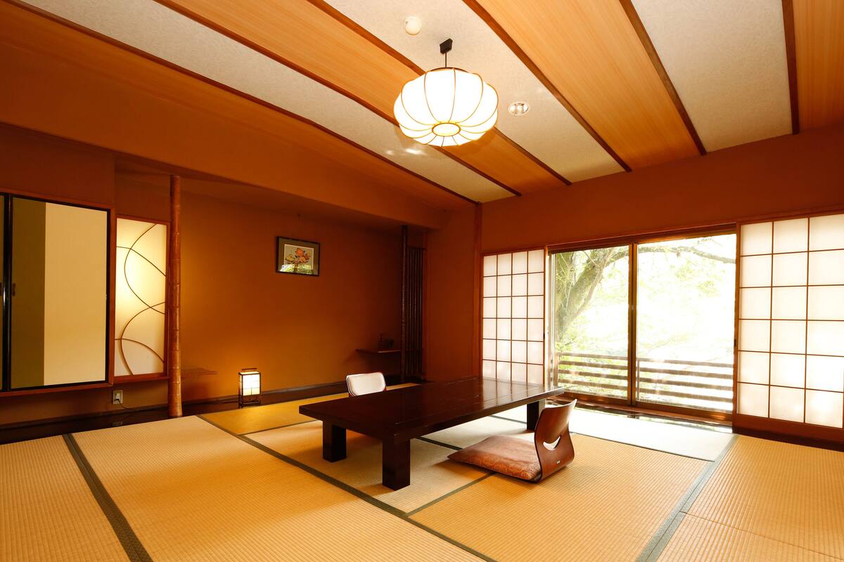 Ein traditioneller japanischer Raum mit Tatami-Bodenbelag, einem niedrigen Tisch und Schiebetüren.
