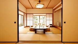 A traditional Japanese room with tatami flooring, a low table, and sliding doors. - Albergo Yuraku (Yugawara)