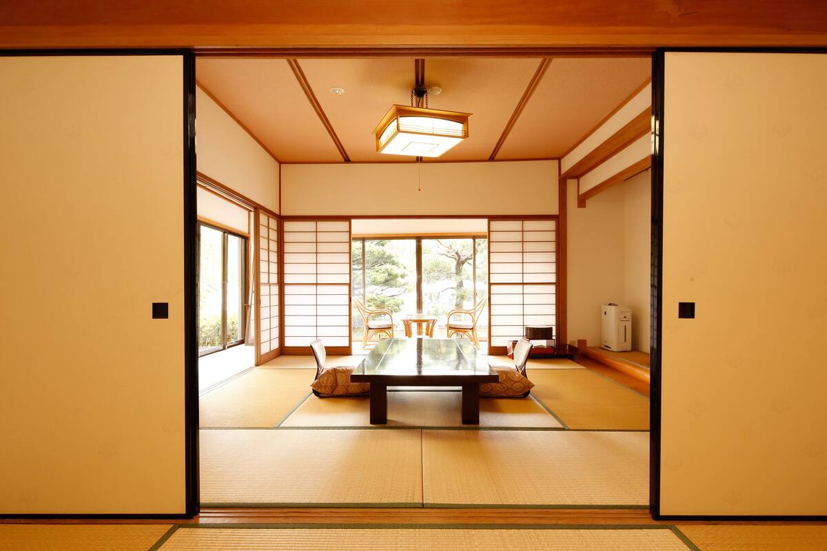 Ein traditioneller japanischer Raum mit Tatami-Böden, einem niedrigen Tisch und gleitenden Schiebetüren.