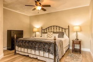 A bedroom with a bed, two bedside tables with lamps, a ceiling fan, and a dresser. - Strictly Moose Luxury Vacation Suites (Gorham)
