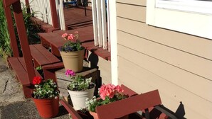 A porch with wooden benches and a wooden cart with potted flowers.