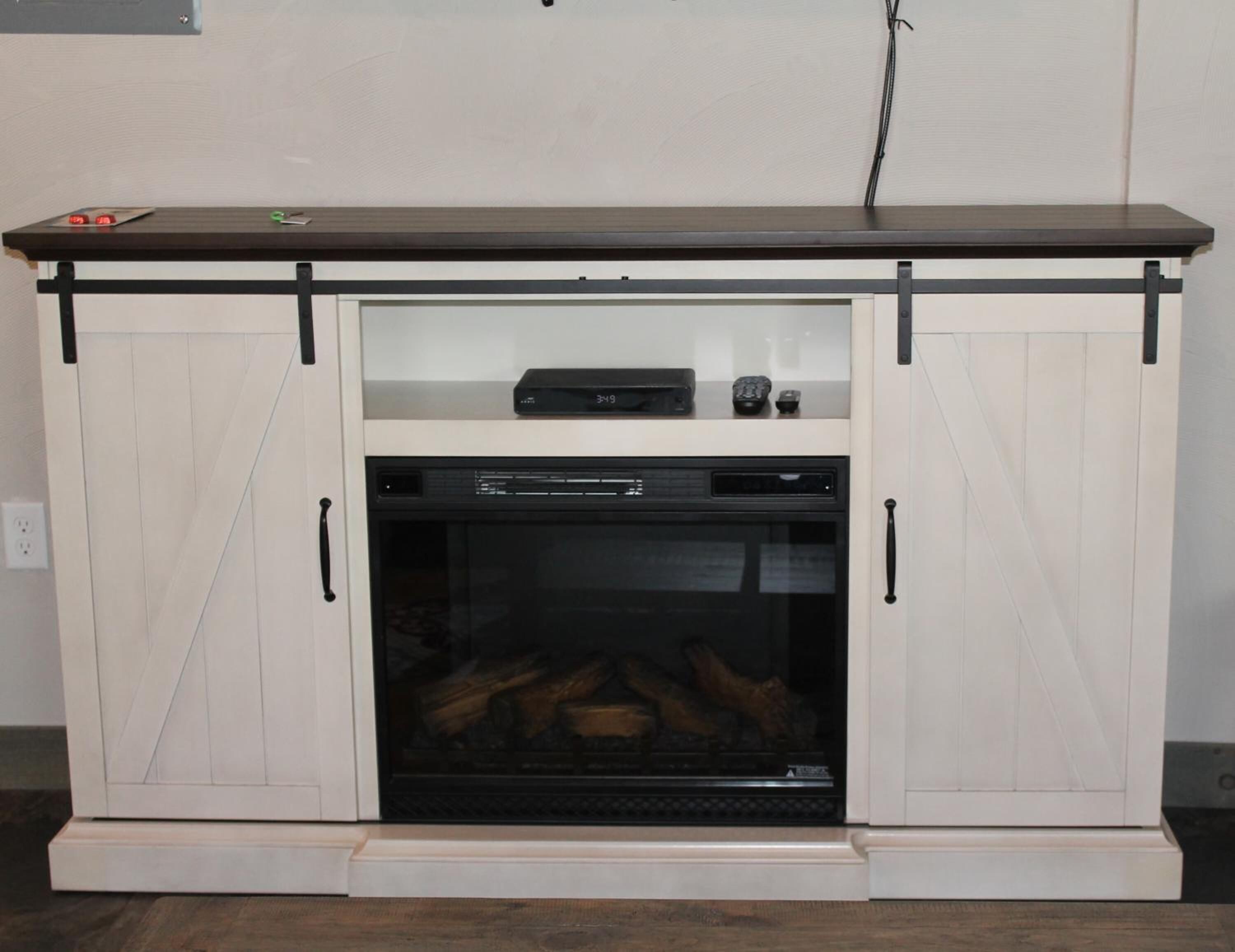 A white cabinet with a black oven and a digital clock on top.