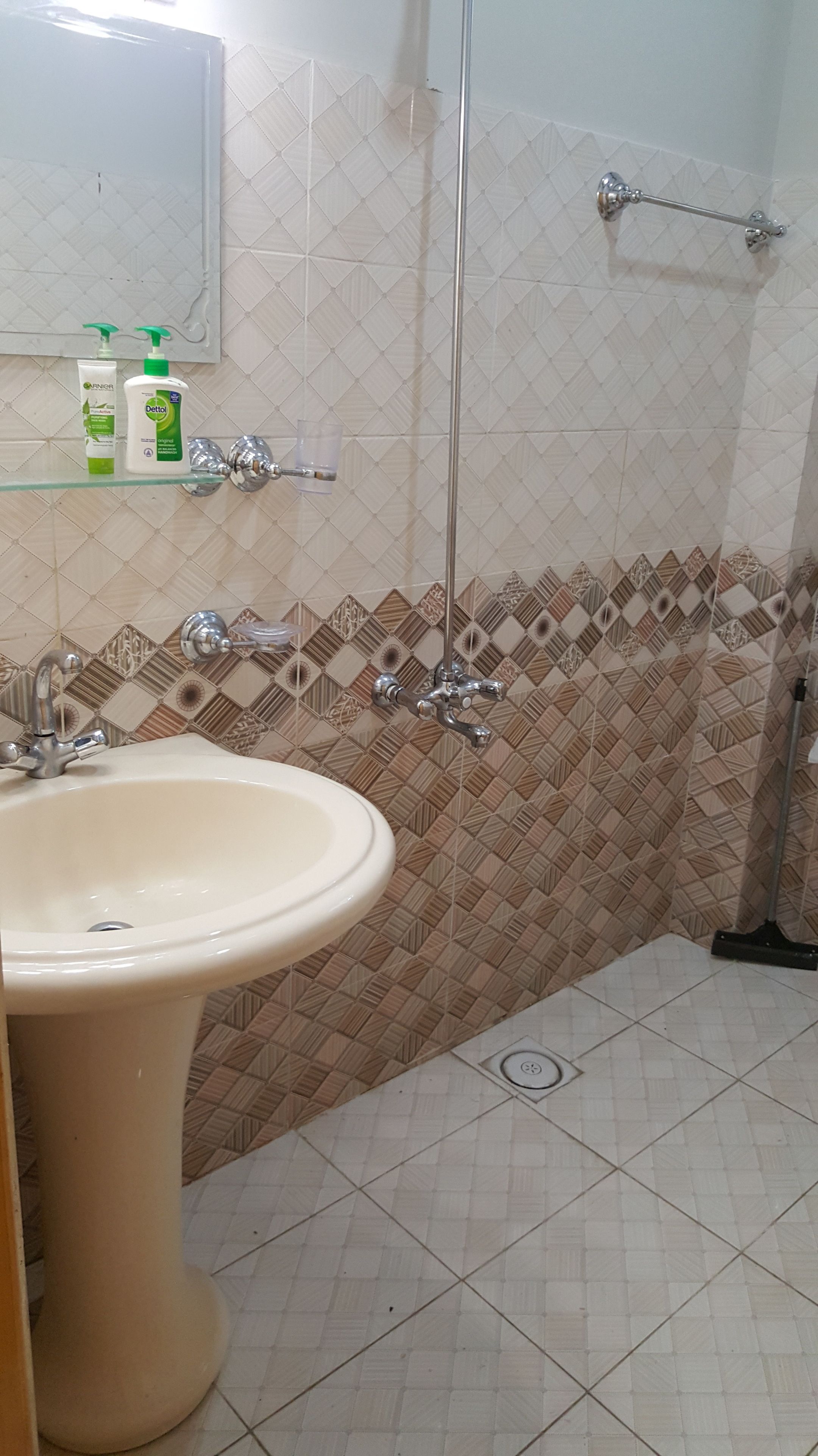 A bathroom with a sink, a mirror, and a shower area.