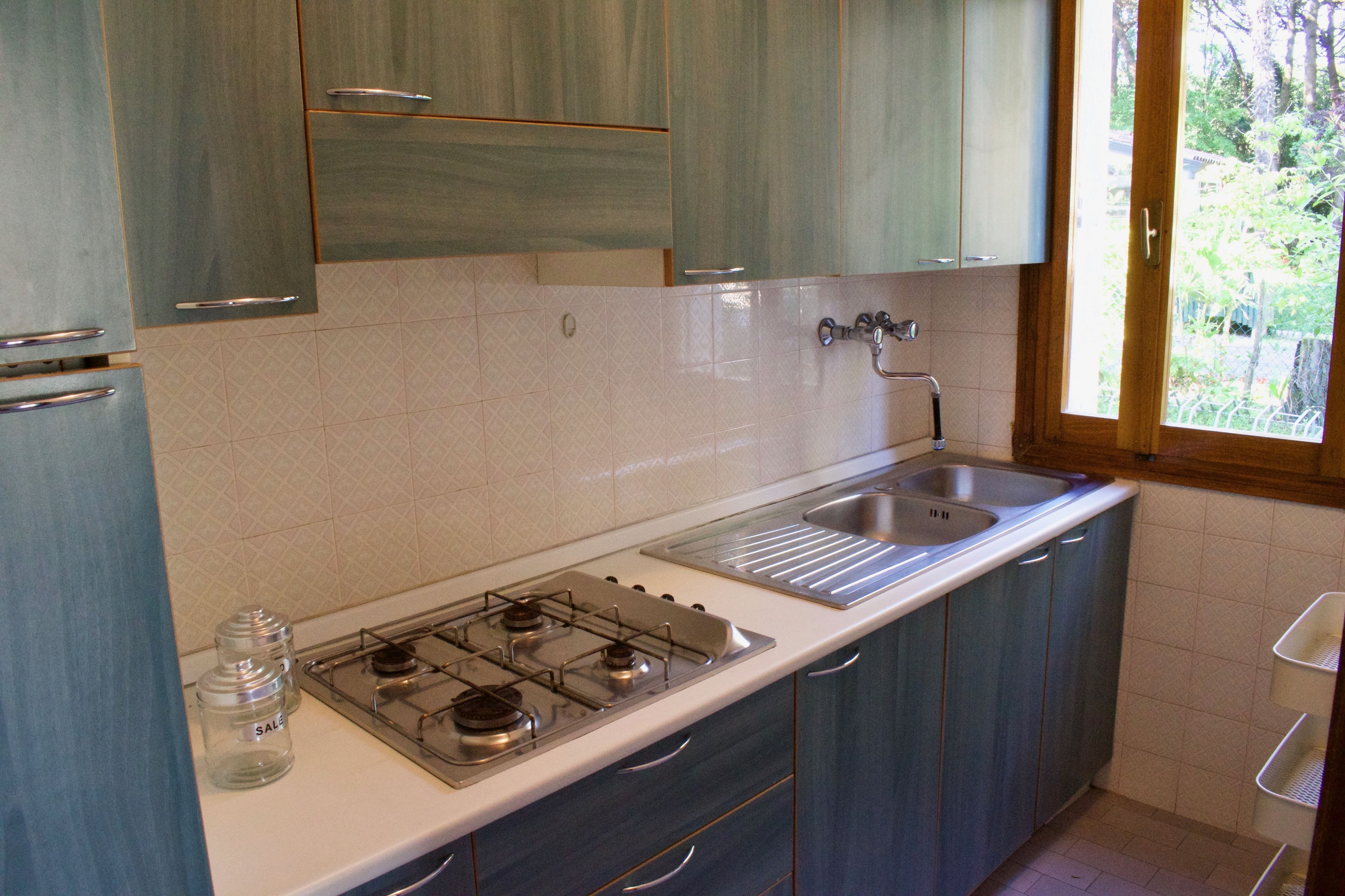 Una cucina con piano cottura a gas, lavandino e pensili.