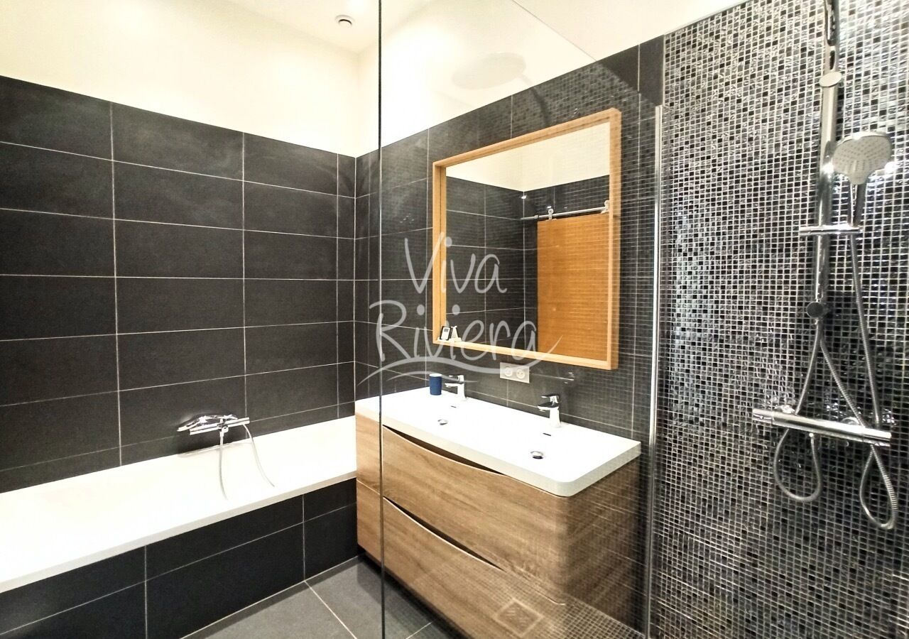 Een moderne badkamer met een bad, wastafel en douche.