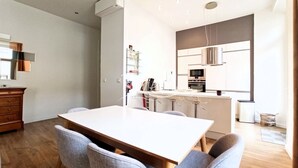Una cucina moderna con mobili bianchi, un'isola centrale e un'area pranzo con un tavolo di legno e quattro sedie.