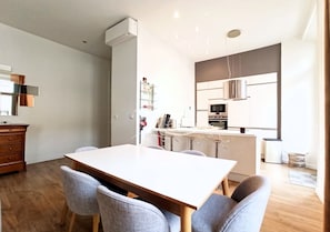 A modern kitchen with white cabinets, a central island, and a dining area with a wooden table and four chairs.