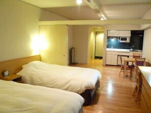 Una habitación de hotel con dos camas, kitchenette y piso de madera.