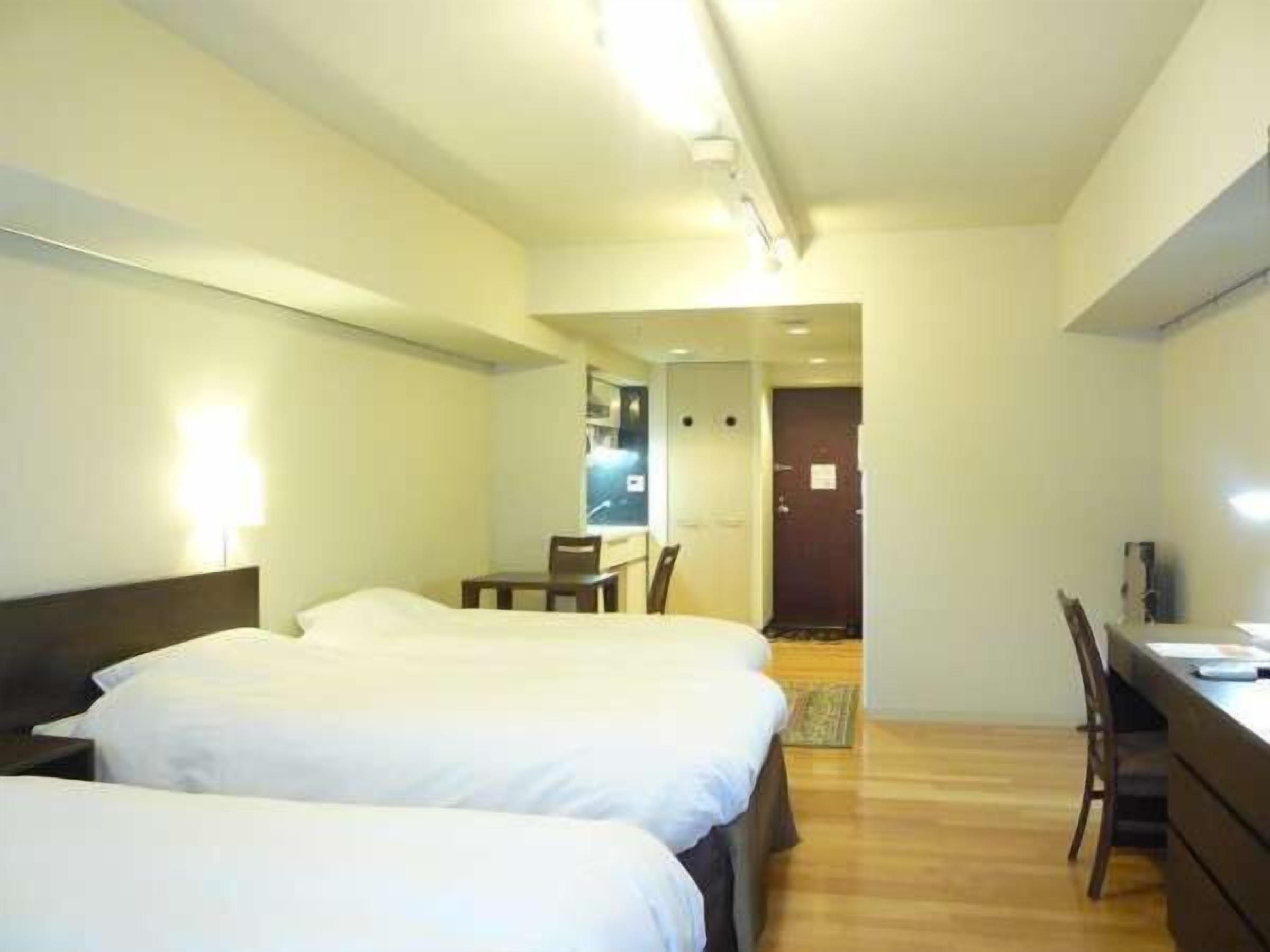 A hotel room with two beds, a desk, and a chair.