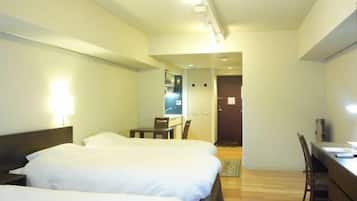 A hotel room with two beds, a desk, and a chair.