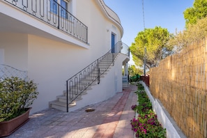A narrow pathway leading to a building with a staircase and a bamboo fence on one side. - Park Hotel Villa Maria (Vico del Gargano)