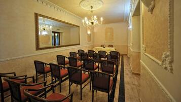 Ein Konferenzraum mit einem großen Spiegel, einer Chandelüster und Reihen von Stühlen.