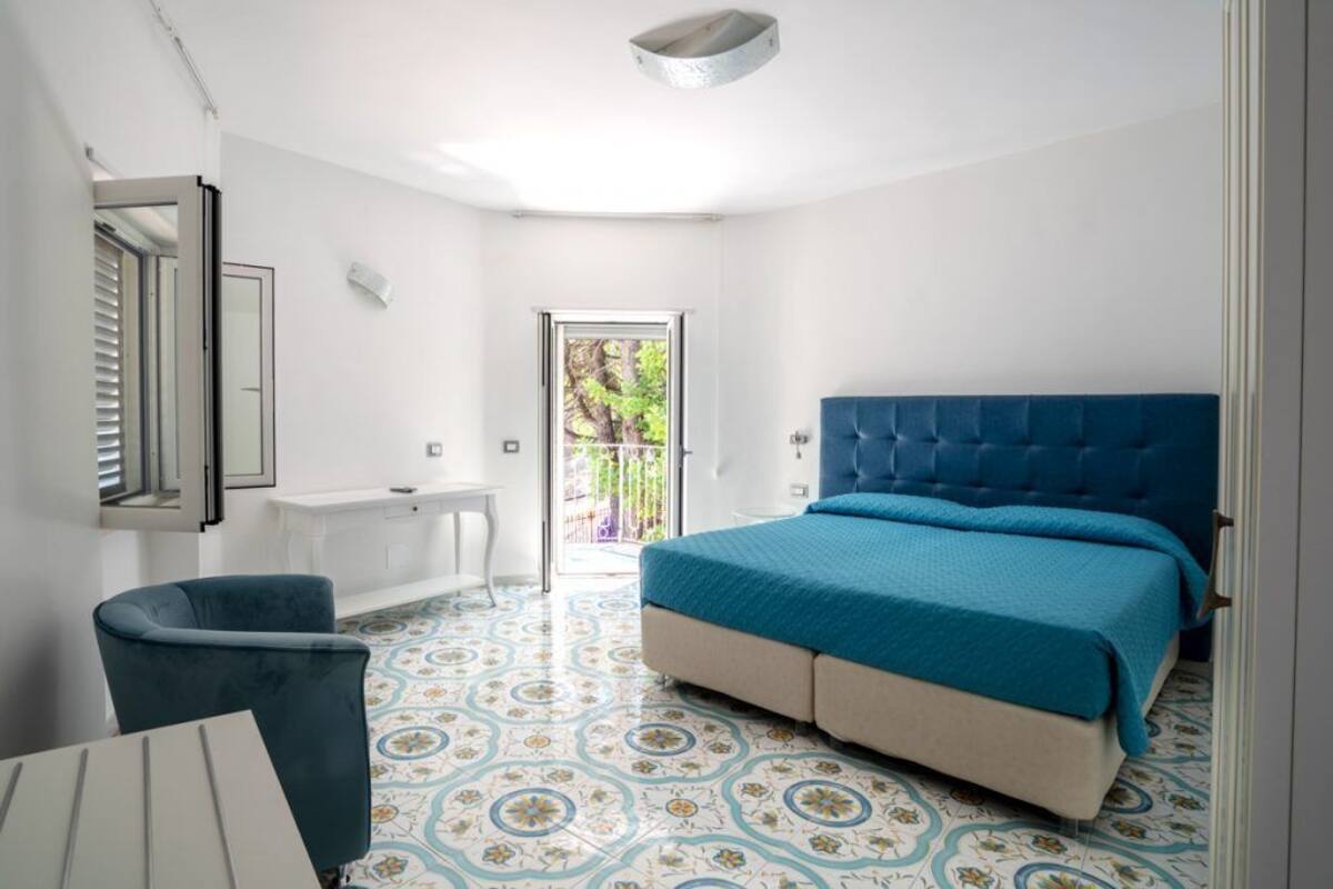 Un dormitorio con una cama grande, un escritorio, una silla y un baño.