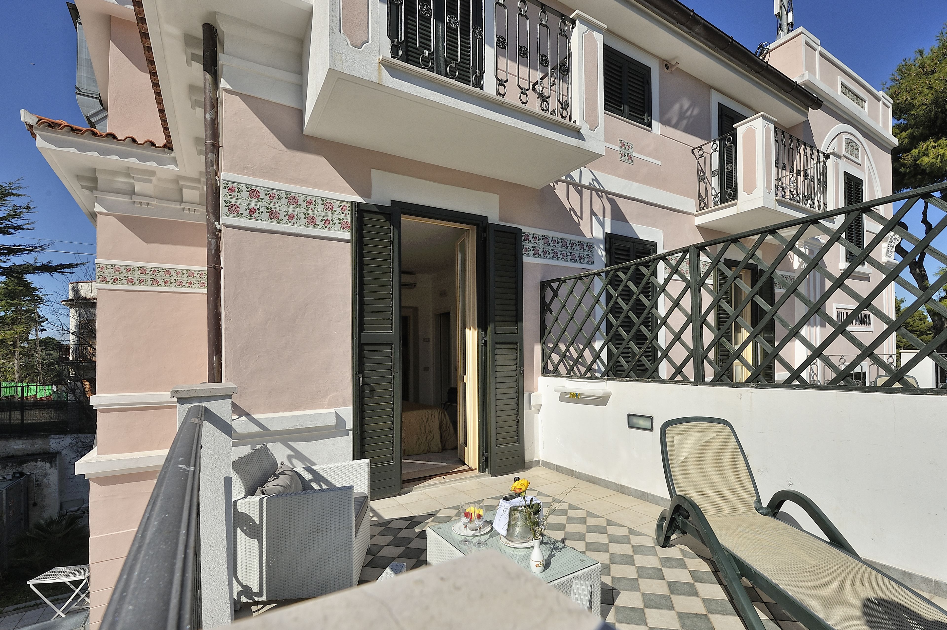 A two-story building with a balcony, a checkered floor, and a table with a chair.