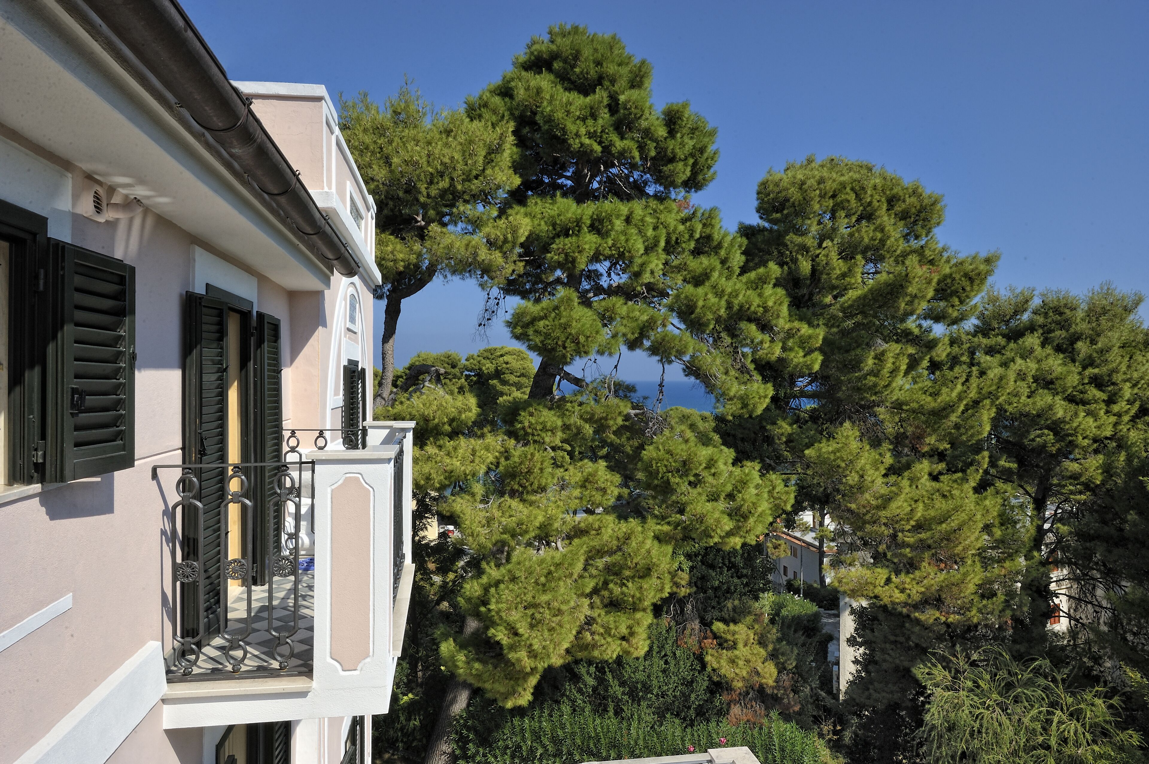 Ein Gebäude mit einem Balkon, umgeben von üppigem Grün.