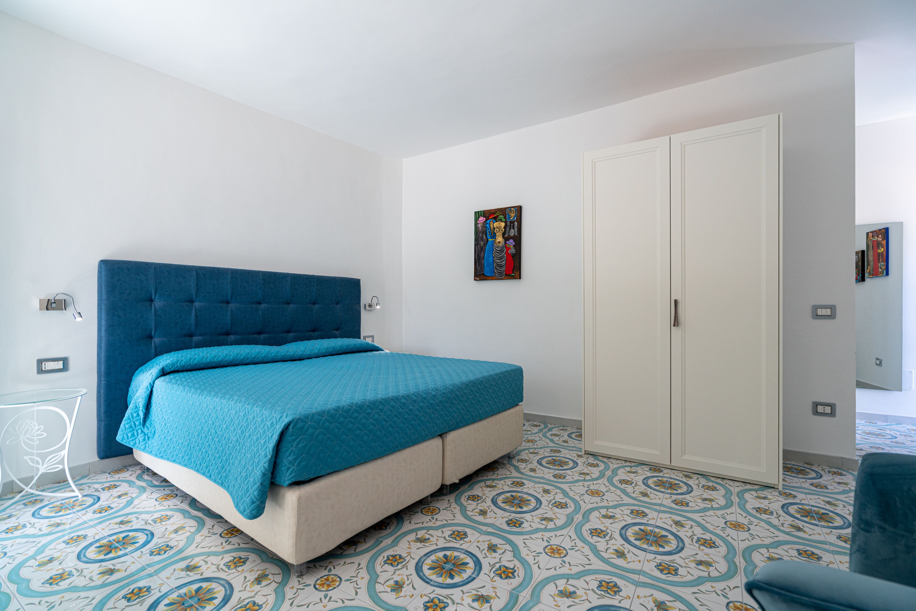Un dormitorio con una cama grande, un armario y una mesita.