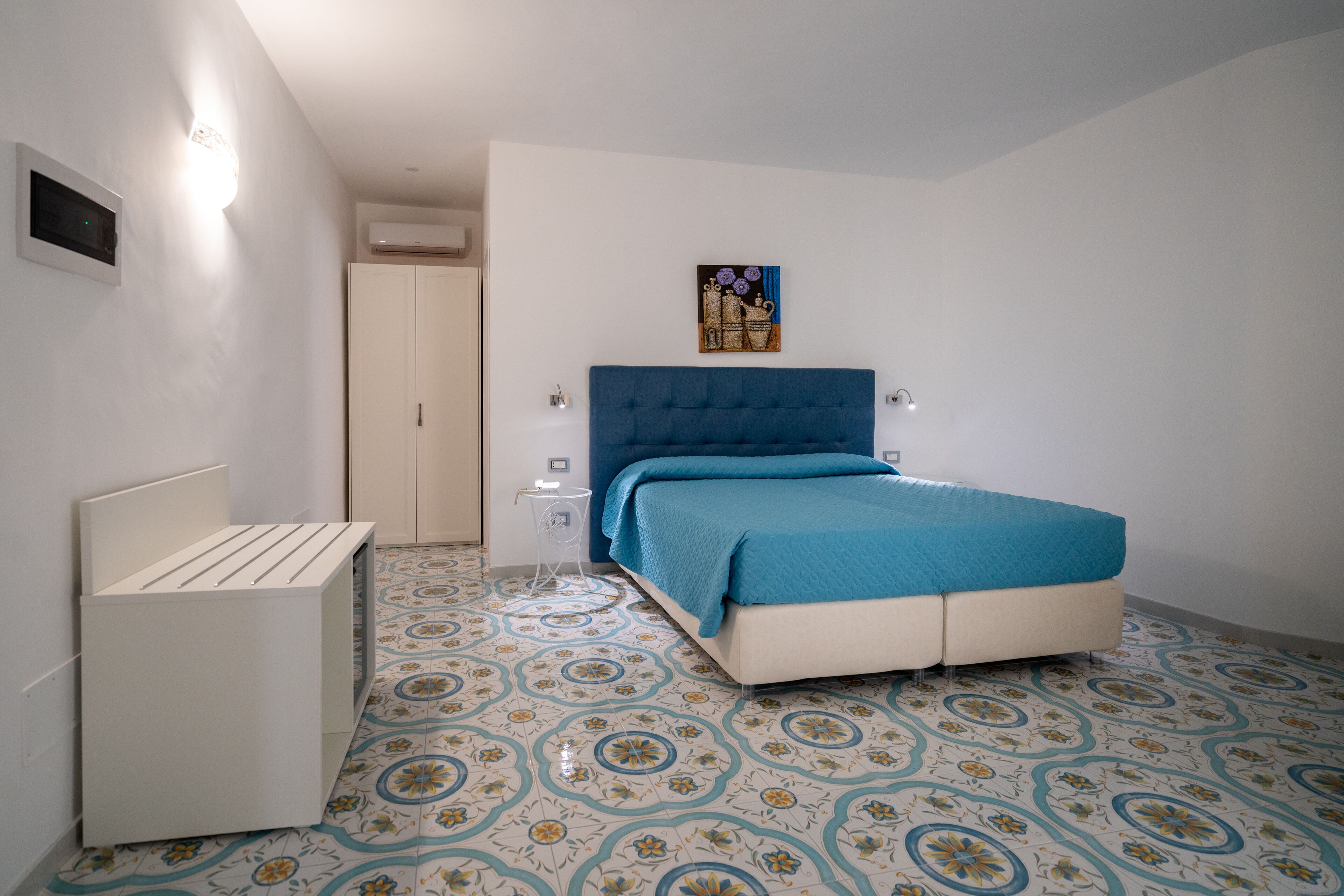 Une chambre à coucher avec un lit, une table de chevet, une armoire et un sol à motifs.