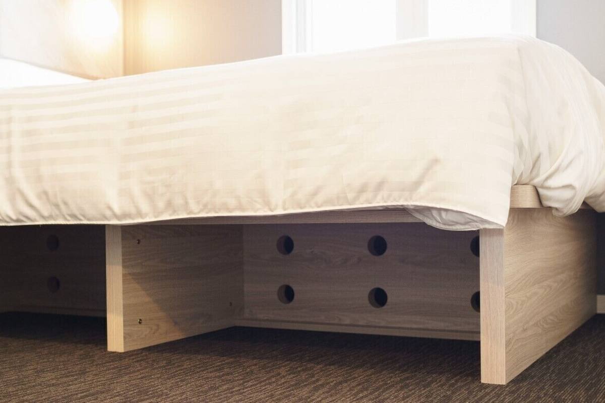 Una cama con estructura de madera y cajones debajo para guardado.